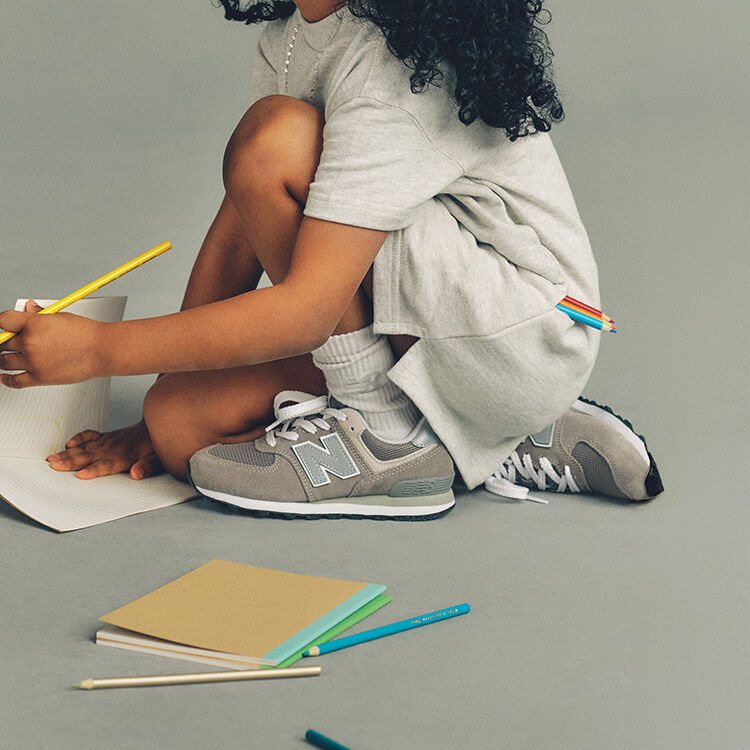 Child sitting on the ground wearing New Balance