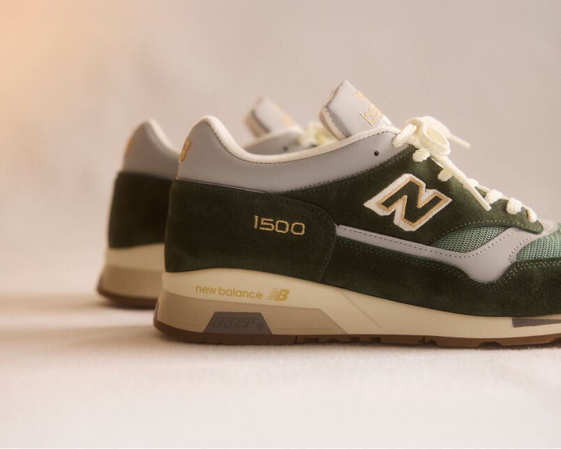 A pair of New Balance Made in UK sneakers on a green textured studio environment. 