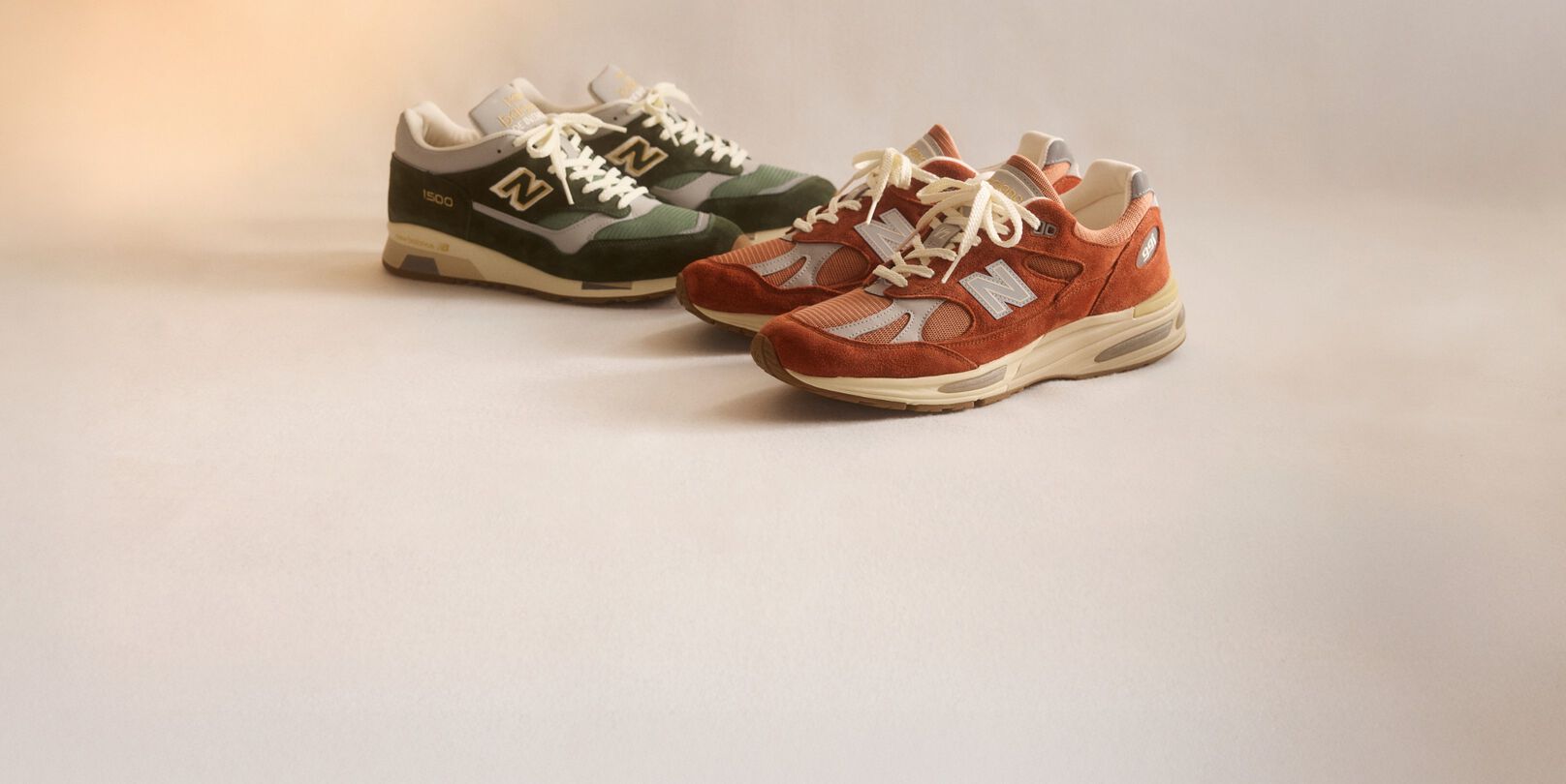 Two pairs of New Balance Made in UK sneakers sitting in a studio.