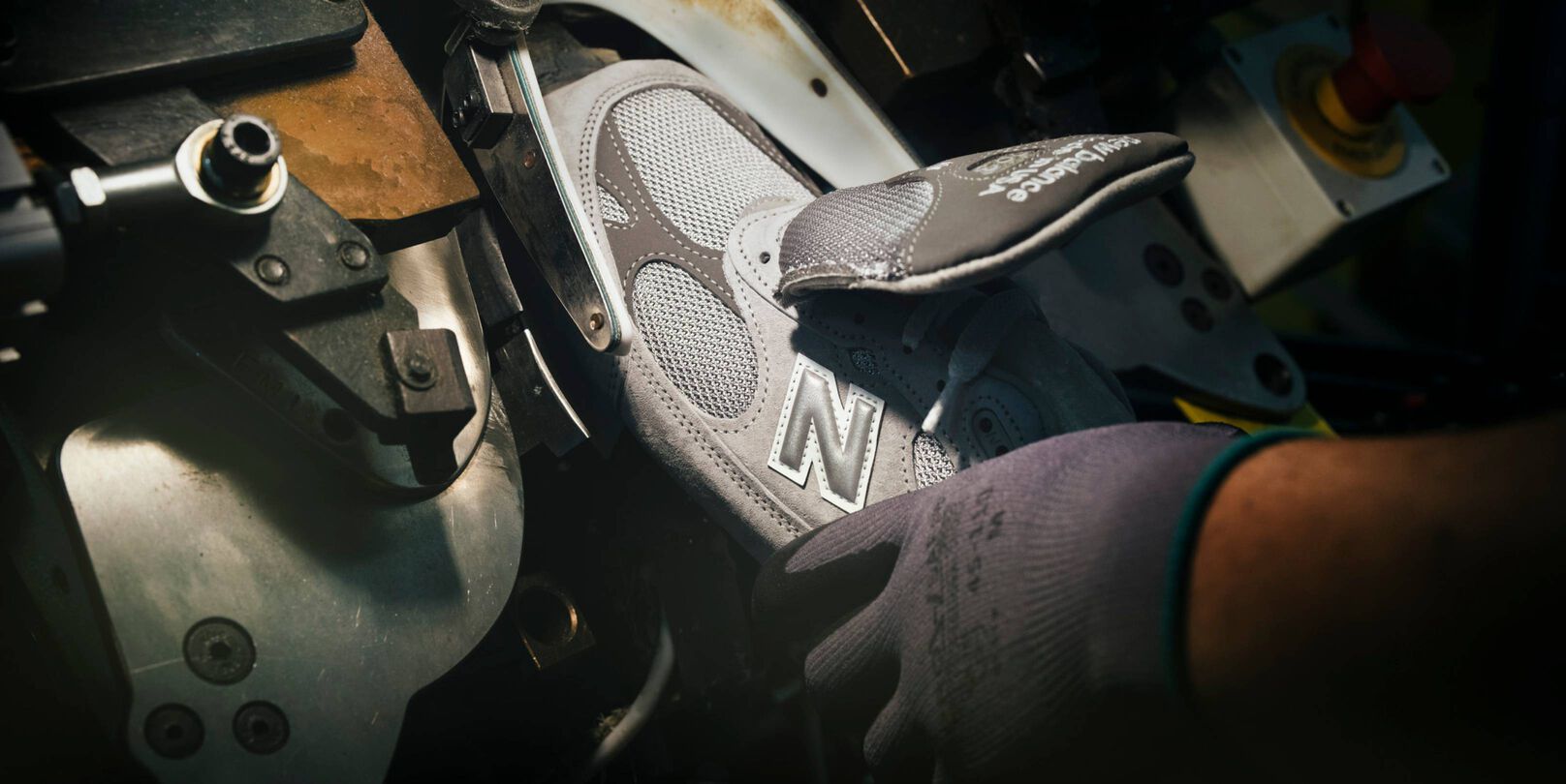 A hand putting a sneaker into a machine during its construction.  