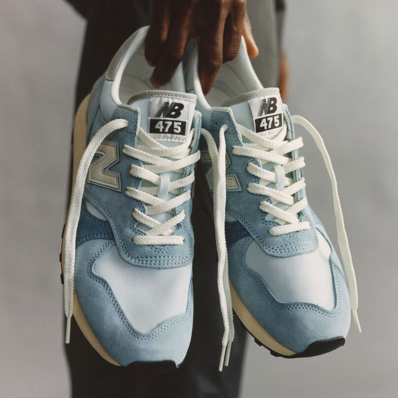 A man holding a pair of New Balance 475 sneakers.